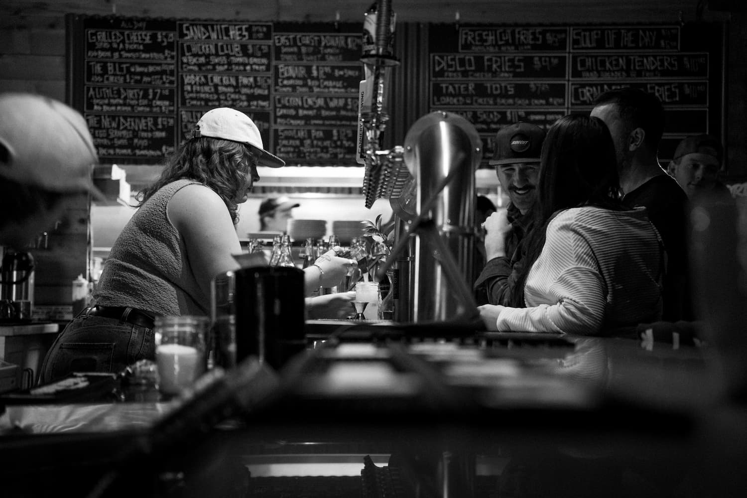 Bartending pouring drinks and smiling customers